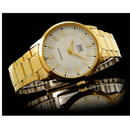 Reloj dorado con esfera blanca sobre fondo negro, reflejando en una superficie brillante.