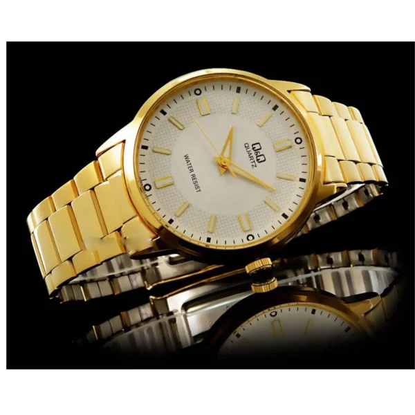 Reloj dorado con esfera blanca sobre fondo negro, reflejando en una superficie brillante.