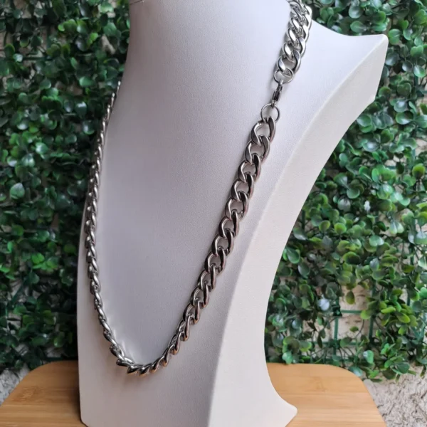 Cadena de acero inoxidable plateada exhibida en maniquí con fondo verde. Título: Cadena de acero inoxidable estilo cubano plateada - Exhibición