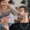 Pareja sonriendo mientras entrega un regalo con la cadena de acero inoxidable Cartier.