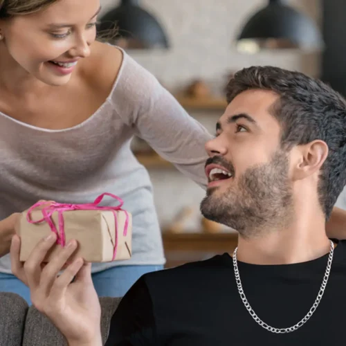 Pareja sonriendo mientras entrega un regalo con la cadena de acero inoxidable Cartier.