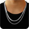 Hombre con dos cadenas de acero inoxidable plateadas sobre camiseta negra.