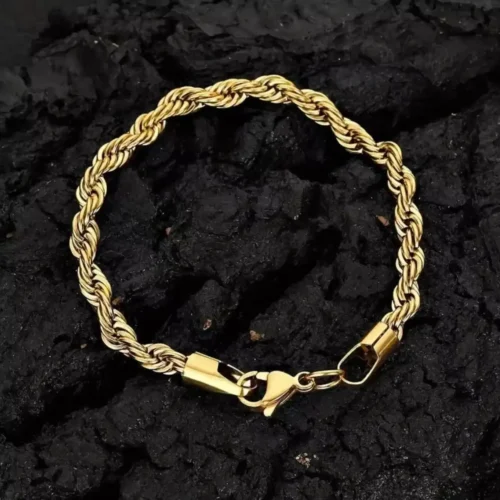 Pulsera dorada trenzada tourbillon sobre una superficie de textura negra.